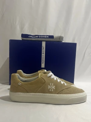 Beige sneakers från Jacob Cohën - Tja! Säljer nu dessa feta beiga Jacob Cohën skor i storlek 41,5 men passar 42-41. Dessa skor är helt nya och allt OG tillkommer.                                                                        Ny pris: ca 5000kr.                                                    Säljs för: 2099kr.                                                             Hör gärna av er om ni vill ha mer bilder eller om ni är intresserade! 
