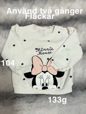 Vit tröja med Minnie Mouse och prickar - Söt vit sweatshirt med svarta prickar och stort tryck av Minnie Mouse med rosa rosett framtill. Tröjan har rund hals, långa ärmar och ribbade muddar. Perfekt för dig som gillar Disney och vill ha en lekfull stil.🌸 Använd två gånger. Fläckar. Storlek 104
