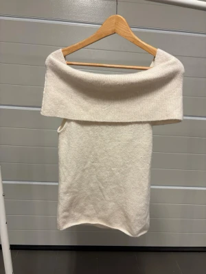 Vit offshoulder top från H&M stickad - Trendig vit offshoulder klänning från H&M i mjukt stickat material. Klänningen har en bred krage som vilar över axlarna och en rak, kort siluett. Perfekt för dig som gillar en enkel men snygg look.