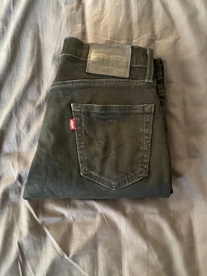  Levi's jeans  - Snygga svarta jeans från Levi's med klassisk femficksdesign och smal passform. Jeansen har Levi's röda logga på bakfickan och patch i läderimitation vid linningen. Tillverkade i slitstarkt denimtyg, perfekta för en trendig och avslappnad stil. Storleken är W29 och L32
