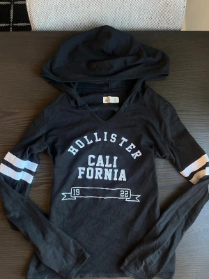  Hollister hoodie  - Snygg Hollister hoodie i svart med tryck och luva i storlek XS