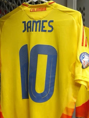 Colombia matchtröja nummer 10 James  - Gul Colombia matchtröja från Adidas med blå detaljer och nummer 10 på både fram- och baksida. Tröjan har röd och blå rand på axlarna, landslagets emblem på bröstet och namntryck 'JAMES' på ryggen. Tillverkad i lätt och ventilerande material.