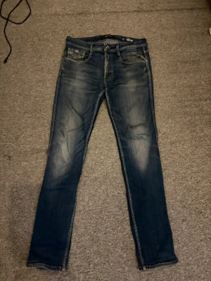 Mörkblå skinny jeans med slitningar - Säljer ett par mörkblå skinny jeans med snygga slitningar och tvättade detaljer på låren. Klassisk femficksmodell med dragkedja och knapp framtill. Jeansen har smal passform och är perfekta för en trendig vardagslook.