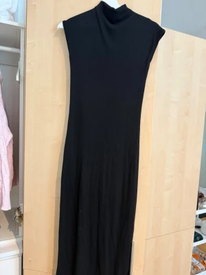 Svart långklänning från Nelly - Svart långklänning från Nelly med hög hals och ärmlös design. Klänningen är ribbad och har en smickrande, rak passform. Perfekt för dig som gillar stilrena och minimalistiska plagg. Nypris 399 mitt pris 100