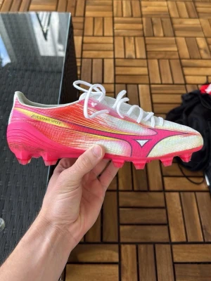 Mizuno Alpha FG Elite - Säljer ett par Mizuno Alpha FG Elite i storlek 40,5 (260mm). Motsvarar ungefär 42 i Adidas och Nike storlek. Använda en träning. Finns ett par använda Mizuno Alpha AG Japan i acceptabelt skick som säljs och kan skickas ihop. Också storlek 40,5.