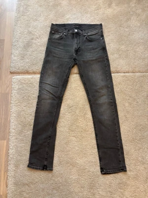 Nudie Jeans Darkgrey - Nudie Jeans Slimfit storlek 32. Köpta på NK Street avdelningen. Använda ett par gånger, i mycket bra skick. Mått och labels finns på bilder. 