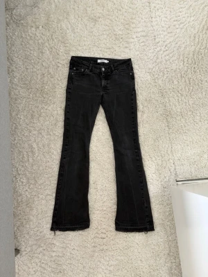 Svarta bootcut jeans med rå kant - Säljer ett par svarta bootcut jeans med rå kant nertill. Jeansen har klassisk femficksmodell, normal midja och lätt utsvängda ben. Jeansen är uppsprättade längs ned.