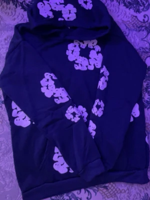 Svart hoodie med vita moln - Säljer en svart hoodie med vita molnliknande tryck över hela tröjan. Hoodien har en klassisk huva och magficka framtill. Perfekt för dig som gillar streetwear och vill sticka ut lite extra med ett unikt mönster.