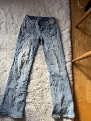 Ljusblå bootcut jeans med fickor - Säljer ett par ljusblå bootcut jeans med fram- och bakfickor. Jeansen är ifrån Madlady. Klassisk denimlook som passar till det mesta. Materialet är denim i bomull. Storlek 34 short.