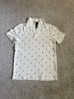 H&M Piké - Vit pikétröja från H&M i Slim Fit med palmtryck. Använd men i mycket bra skick utan hål eller tydligt slitage.  Säljs då den inte används längre.  📦 Snabb leverans! 💬 Hör gärna av dig vid frågor eller om du vill ha fler bilder/mått!