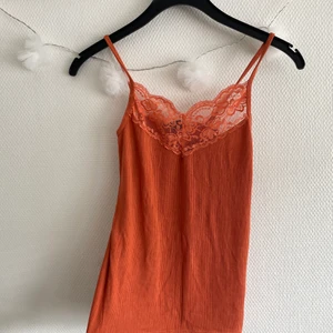 Oranged linne med spets! - Jättefint ribbat linne med spets! Sitter inte så tajt på mig för referens, väldigt strechigt! Använt ett par gånger