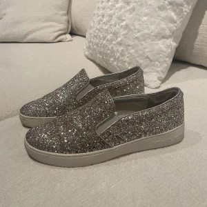 Michael Kors Skor - Silvriga/glittriga Michael Kors skor, köpta i Michael Kors butik 2 år sen använd en gång på bröllop. Storlek 38 men passar som 38/39. I väldigt gott skick! Nyköpta för 2.500 säljer för 600