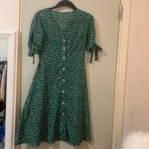 Grön blommig klänning  - Knälång klänning, med fin detalj på armarna 
