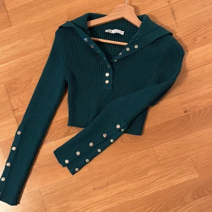 Stickad crop tröja - Grön stickad tröja med guld knappar. Kan öppnas upp eller stängas. Cropped. 