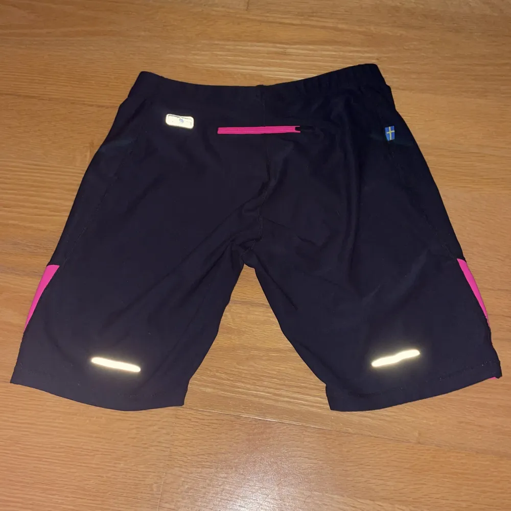 Cykelbyxor med mindre reflexer En bakficka Med rosa på yttersidorna av varje ben Jättebra skick Material: 88% Polyester 12% Spandex. Shorts.