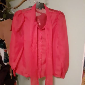 Rosa Blus  - Vacker rosa blus från Ginatricot. Tyget är mesh och lätt genomskinligt. Den har två tygrämsor vid kragen som går att knyta i en rosett. Knappt använd och så gott som ny.💖 Frakt: 45kr 