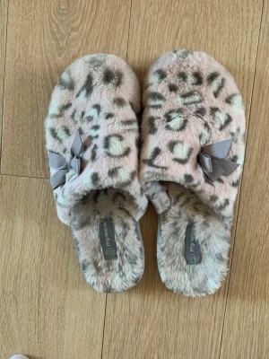 Tofflor  - Ett par tofflor i rosa leopard med en rosett. Använda några gånger men är i fint skick. (Jag har bara haft dessa med strumpor). Storlek 38/39.
