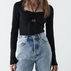 Svart topp - En svart topp från Gina Tricot med snöre och slits på ärmarna. Storlek M, aldrig använd, endast provad. Lapparna sitter kvar. 