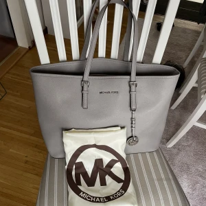 Michael Kors Jet Set Leather bag 2019 - En medelstor grå Michael Kors Jet Set Leather bag från 2019 i fint skick. Väskans handtag är lite smått slitna men utöver det är väskan i väldigt bra skick. Detaljbilder finns om så önskas! Förvaringspåse från MK ingår. 