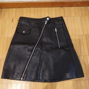 Svart Skinnkjol  - Svart skinnkjol från H&M i storlek 32. Kjolen är hög i midjan och har en A-linjeform.  • Betalning sker via Swish  • Hämtas upp i Vällingby 