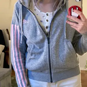 En grå-rosa zip up-hoddie ifrån Adidas. Den är inte oversized. Knappast använd 💕