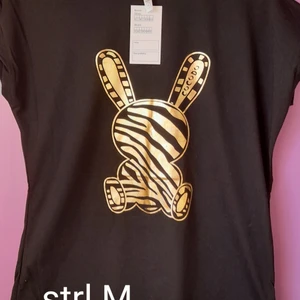 Ny T-shirt  - Ny, mycket vacker blus med korta ärmar i svart med broderad guldhare, storlek M.