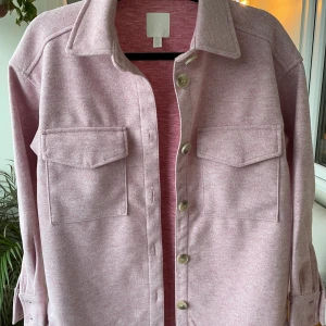 Rosa vårjacka strl S - Nevermind min halvdöda växt i hörnet men här är en härlig ljusrosa skjortjacka i storlek S. Endast provad så i toppskick! Perfekt till när det förhoppningsvis blir lite varmare ☀️ Den är oversize så skulle säga att den passar XS-M beroende på hur man vill ha passformen.