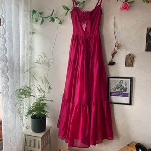 Unik balklänning  - Unik vintage balklänning i utmärkt skick med keyhole detalj och knytning. Den är lång och dramatisk. Mörkrosa med en ljusrosa lining. Passar XS-S, saknar lapp så storleken är uppskattad. Köpt på Beyond Retro för 2500kr