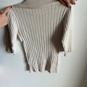 Polotröja - Krämvit polotröja med ränder och kroppsdelar armar. Ett bra basic plagg, men har inte kommit till användning i min garderob