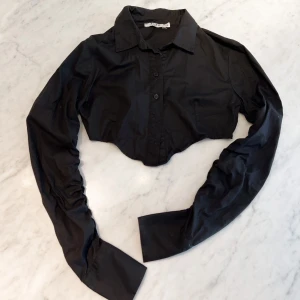 Kort svart skjorta med scrunch  - Kort svart skjorta med ”scrunch” på ärmarna. 