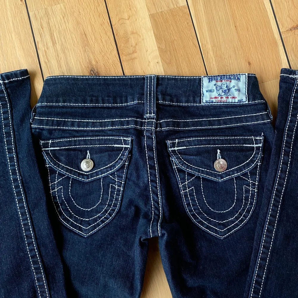 Äkta supersnygga lågmidjade True Religion jeans i mörkblå 💙 Innerbensmåttet är 82 cm och midjan är 71 cm runtom (stl 25). Dem har passformen straight. Säljer pga att de tyvärr är för långa för mig (164 cm) köpare står för frakt, skriv för fler bilder 😊. Jeans & Byxor.