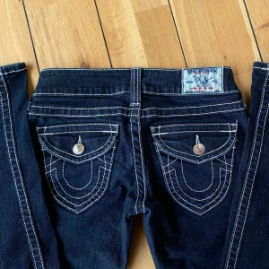 True Religion jeans mörkblå - Äkta supersnygga lågmidjade True Religion jeans i mörkblå 💙 Innerbensmåttet är 82 cm och midjan är 71 cm runtom (stl 25). Dem har passformen straight. Säljer pga att de tyvärr är för långa för mig (164 cm) köpare står för frakt, skriv för fler bilder 😊