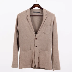 Stickad kavaj från Tiger of Sweden - Kavajformad cardigan från Tiger of Sweden i en blandning av ull och bomull. Passar perfekt som ett alternativ till den udda kavajen för de lite ledigare dagarna, eller matcha den med en ljusare uddabyxa och skjorta, så är du redo för sommarfesten.