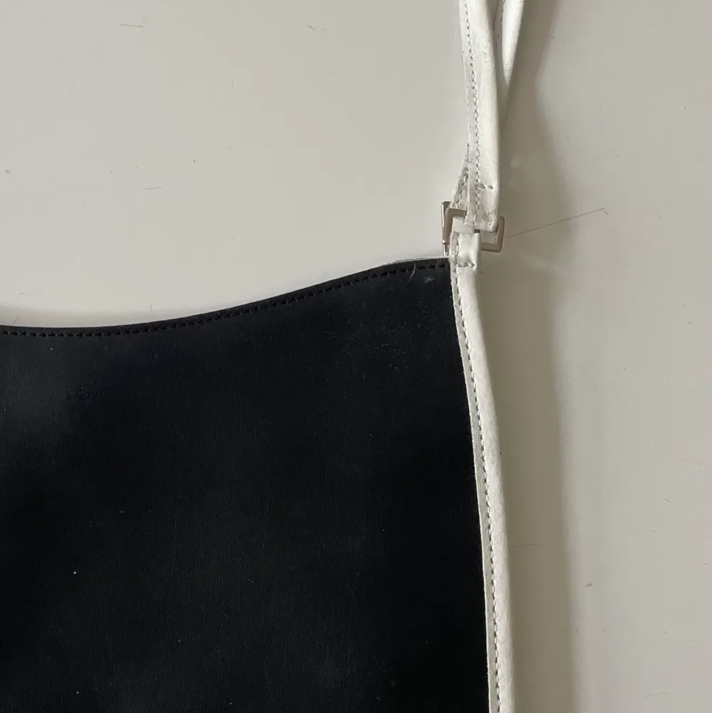 Platt svart handväska med vita och silvriga detaljer. Köpt secondhand men aldrig använt, superfint skick! 🃏. Väskor.