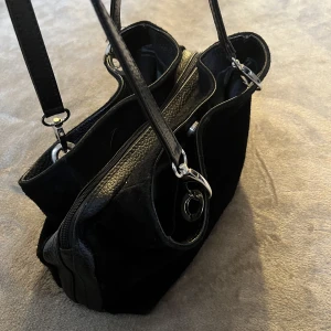 Svart väska - Svart väska med måtten 20x30cm. Tre stora fack som rymmer en hel del mindre grejer. Använd men inga skador på väskan. Ser ut som när jag köpte den🛍️väskan är liten!!!! 