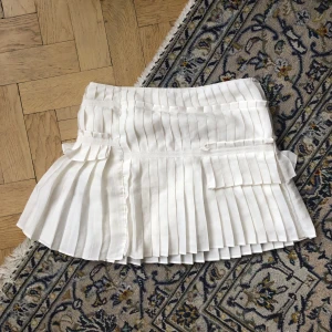 Plisserad kjol, mini-skirt, asymmetrisk  - Asymmetriskt plisserad kjol från Hunkydory! Low waisted i storlek S men funkar nog på en M också. Så galet galet söt! 🧁🥛🎂inga synliga defekter, skriv om du vill ha fler bilder ✨❤️🫡