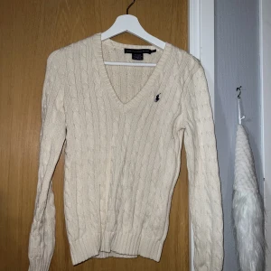 Ralph Lauren tröja - En kabelstickad Ralph Lauren tröja i krämvit färg. Säljes då den bara hänger i garderoben.