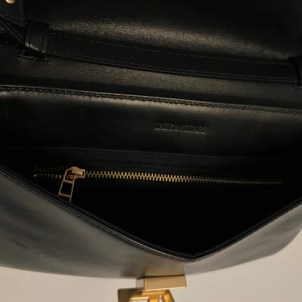 Stilren Zadig & Voltaire Clutch i svart läder med guld initialer. Dragkedjefack på insidan Justerbara remmar med gulddetaljer. . Laukut & Käsilaukut.
