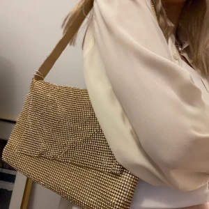 BIANCA x NELLY väska - Superfin glittrig guldig väska från Bianca x Nelly. Aldrig använd. Tillhörande påse kommer med💛🪩Köparen står för frakten.