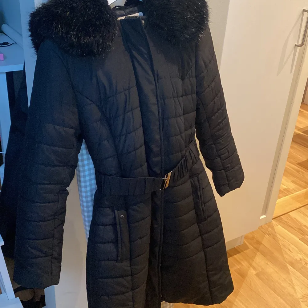 Long puffer coat from French Connection with faux fur hood and elasticated waist belt. Jackor.