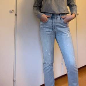 Ett par ankellånga ljusblåa Levi’s jeans 501. Jeansen har knappar framtill, fickor baktill, och lite slitningar (bla slitet hål på vänster knä). Storlek 26/30. Använda ytterst få gånger. Köparen står för frakten. 