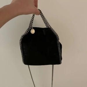 STELLA MCARTNEY VÄSKA I SVART - (Säljer åt en kompis) Säljer nu denna så coola Stella väskan❣️❣️ Den köptes på Stella McCartneys hemsida för 7000 kr❤️ Den är i väldigt bra skick och ser nästan ut som oanvänd❣️ den är perfekt till både fest och vardag då man kan ha den crossbody och hålladen
