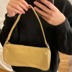 Väska - Fin väska i beige/gul färg fårn Åhléns i fint skick då den knappt är använd! Köparen står för frakten annars möts jag även upp 🥰