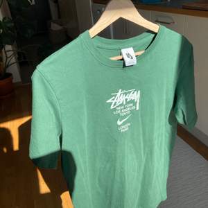 Grön T-Shirt från Nike X Stussy samarbete. Bra skick inte använd mycket, storlek L men skulle säga att de har en mindre passform så denna sitter ungefär som en M. Svåra att få tag på! Säljs på StockX för över 150$ :) säljer då jag har en likadan vit. 