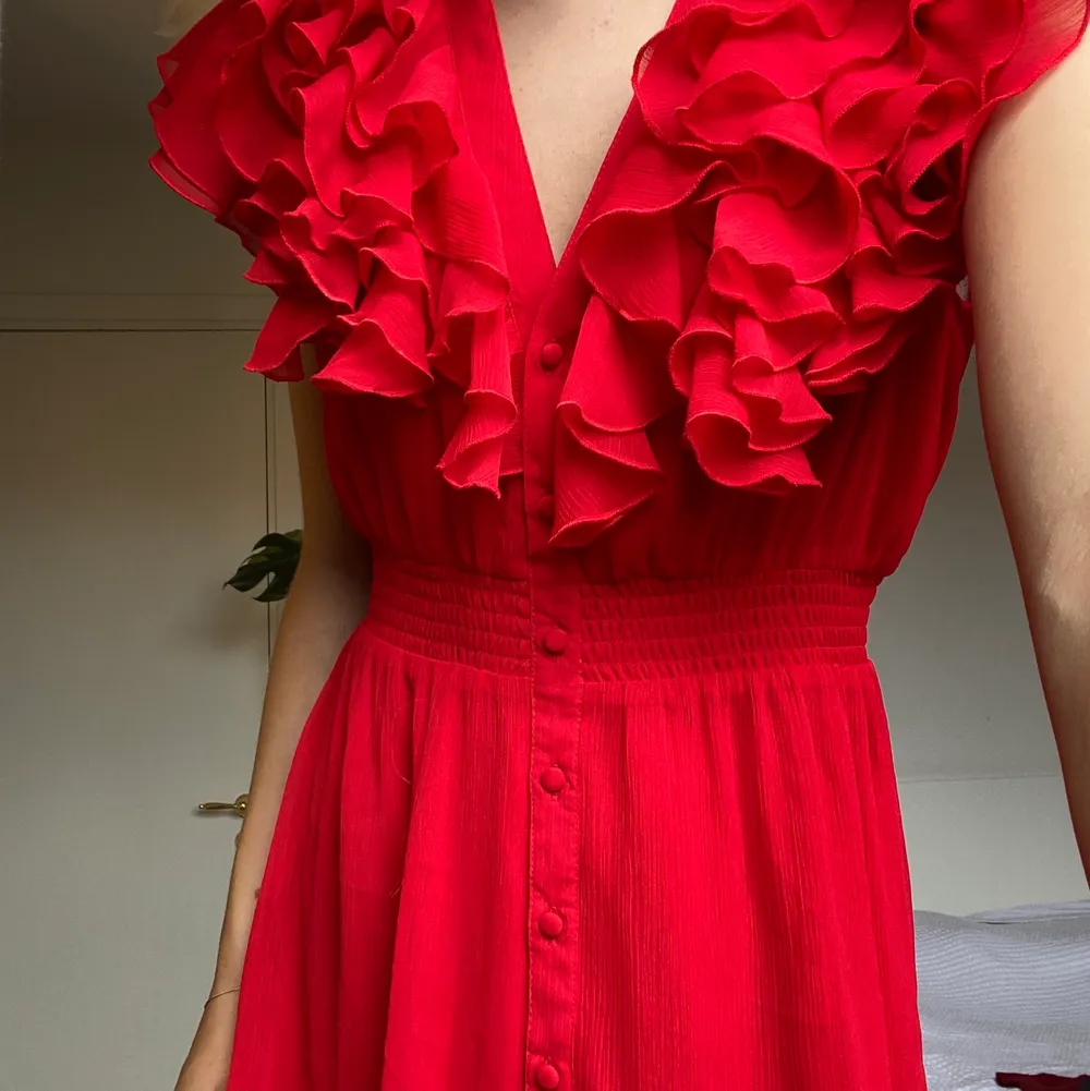 En röd klänning från H&M med knäppbara knappar och volang. 100% polyester. Tvättas i 40°C. ✨. Klänningar.