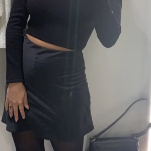 Kort satinkjol  - En kort svart satinkjol.