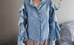 Jeansskjorta med volanger stl xs men mer S - XS men mer stor S. Jättefin och jag får alltid kommentarer när jag har den. Fin både sommar och vinter. Allra bäst till jeans och sneakers tycker jsg. Bomull och fint skick. 