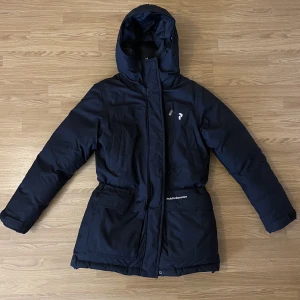 Peak Performance dunjacka S svart - Svart dunjacka från Peak Performance i storlek S. Fyllning 90% ankdun och 10% ankfjäder. Väldigt varm jacka så passar perfekt till kalla dagar. Jackan är i fint skick. Normal i storlek. Går under rumpan på mig som är 165cm. Dragsko i midjan.