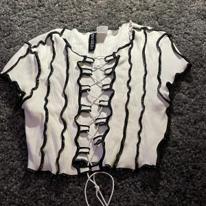 Topp - En vit topp med svart snörning. Väldigt showy och festlig. Passar inte bra på mig.❤️ knappt använd