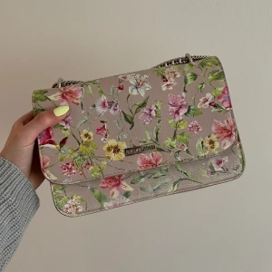 Don Donna väska - En somrig och blommig väska från Don Donna med silver kedja som axelrem, 2 innerfack. Skickar naturligtvis mer bilder om så önskas! Priset kan diskuteras vid snabb affär!